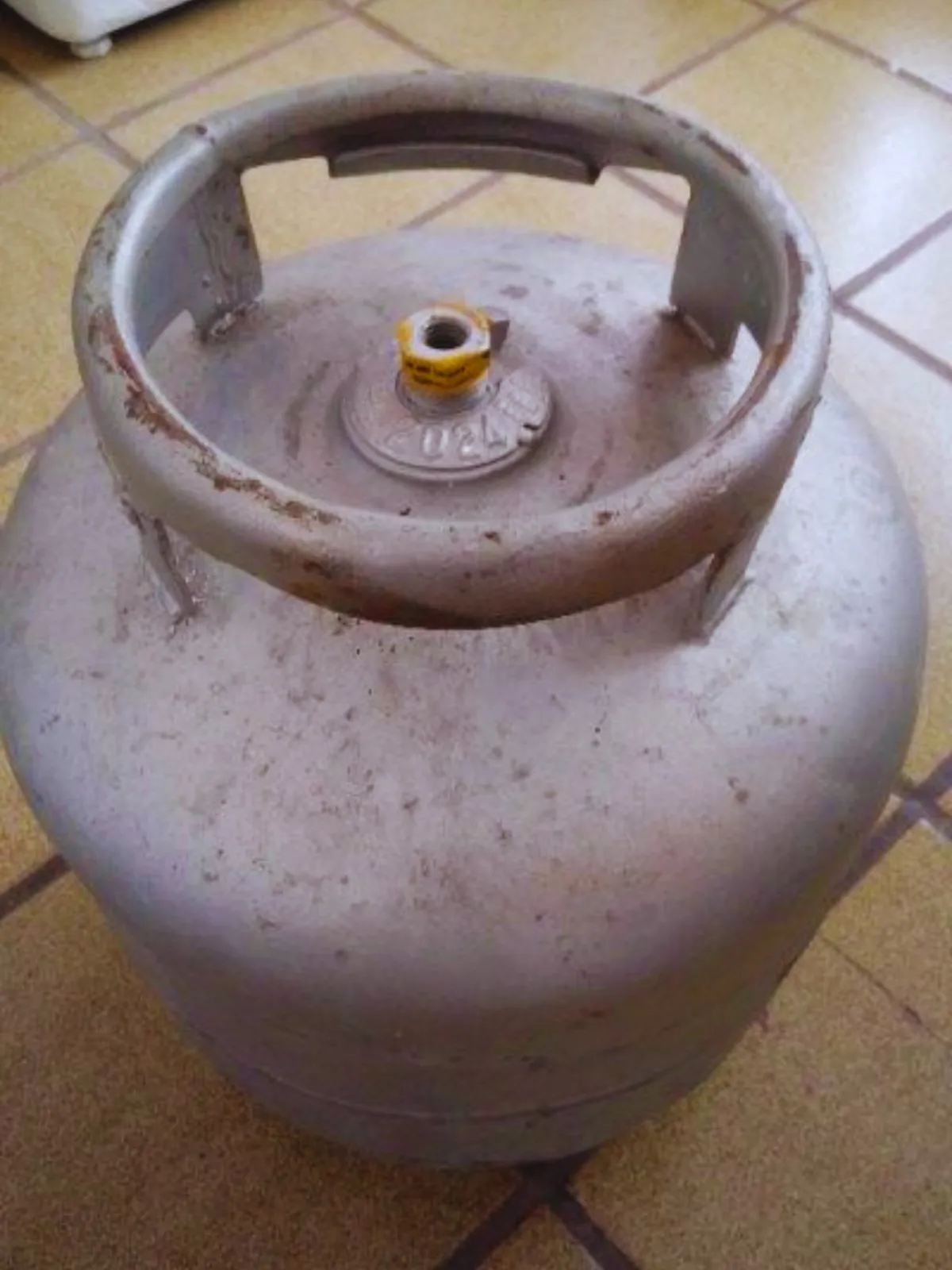 Botijão P13 visto de cima, com a válvula e o lacre amarelo