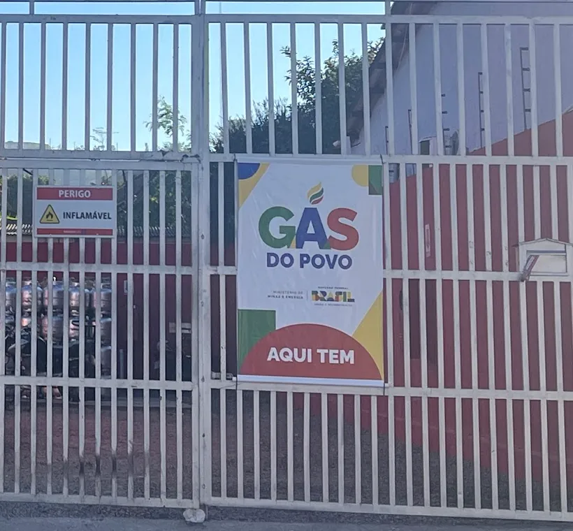 Cartaz do Gás do Povo com a frase Aqui tem, preso no portão branco da Sad Dias Gás