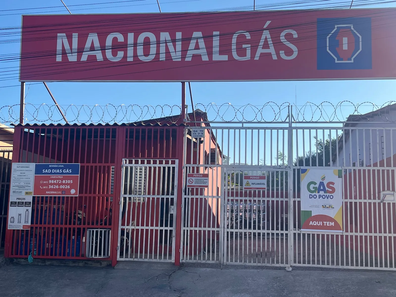 Portão da Sad Dias Gás com a placa Revenda legal, os telefones e o cartaz Aqui tem Gás do Povo