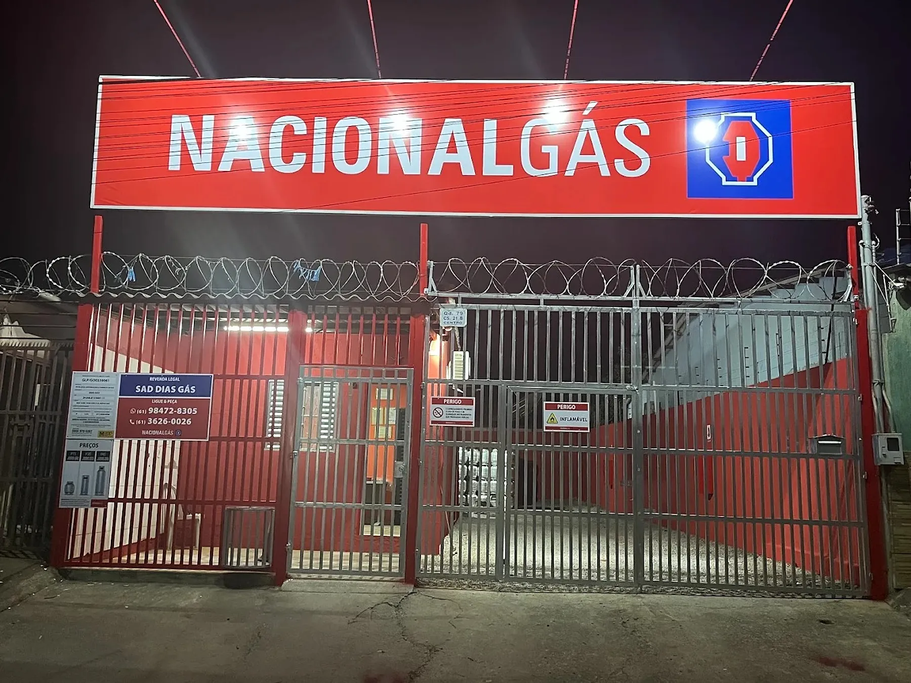 Fachada da Sad Dias Gás à noite, com o letreiro vermelho da Nacional Gás aceso