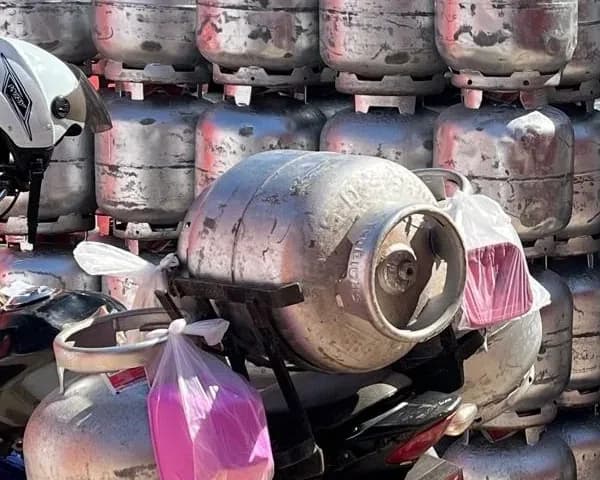 Botijões no bagageiro da moto de entrega, com as sacolas rosa da vasilha de brinde amarradas