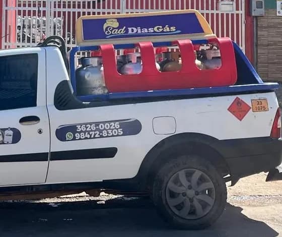 Detalhe da picape da Sad Dias Gás: letreiro azul e dourado no teto, gaiola vermelha e o WhatsApp 98472-8305 na lateral